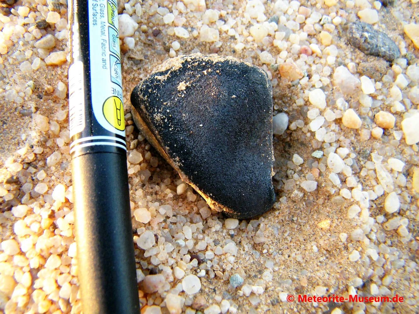 Almahata Sitta Individuum Meteorit mit schwarzer Schmelzkruste auf dem Wüstensandboden